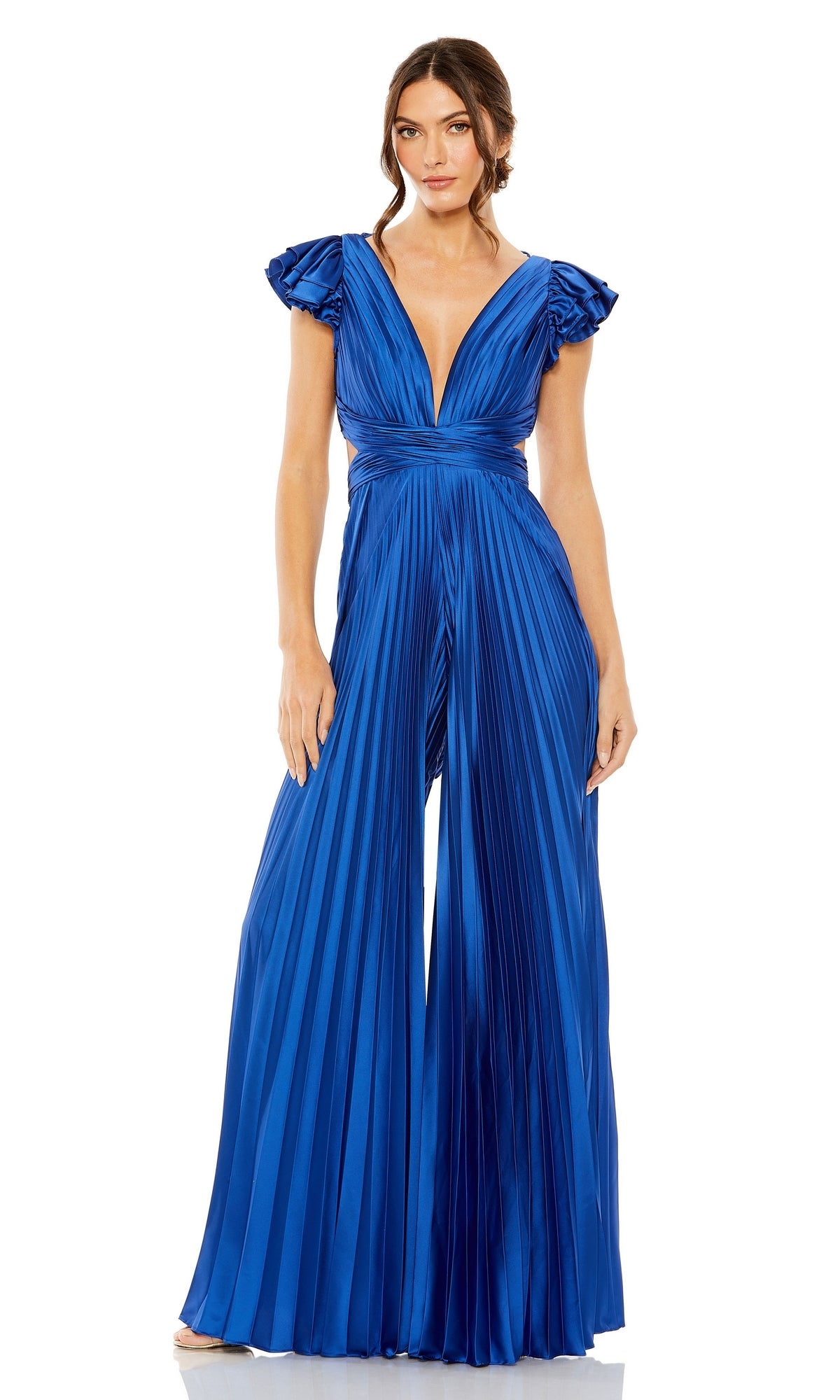 A woman wears the Pleated Formal Jumpsuit 27361 by Mac Duggal, featuring royal blue pleats, a deep V-neckline, short ruffled sleeves, and a stylish lace-up back.